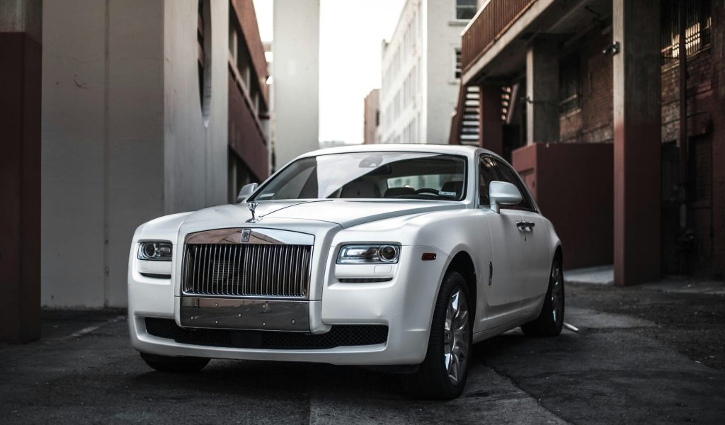 Elegant white luxury car parked in an urban alley, exuding sophistication and style.